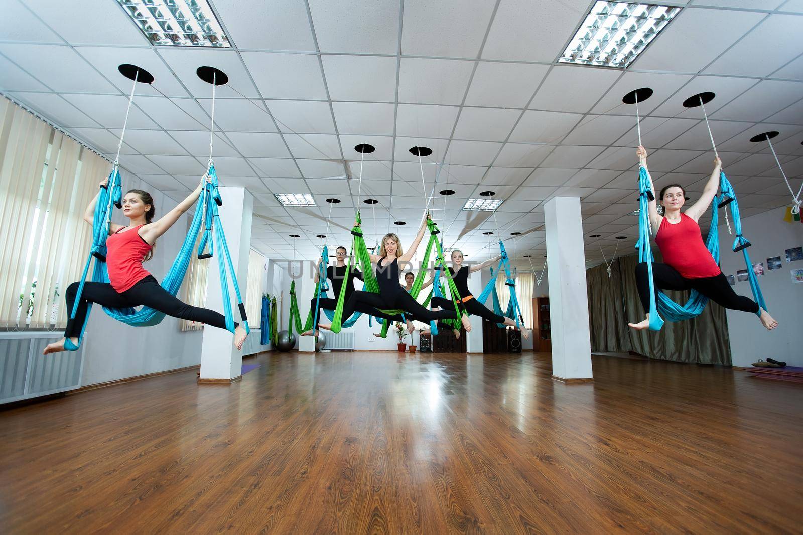 Group of young people practicing yoga on hammock at health club. Fitness, stretch, balance. by StudioPeace