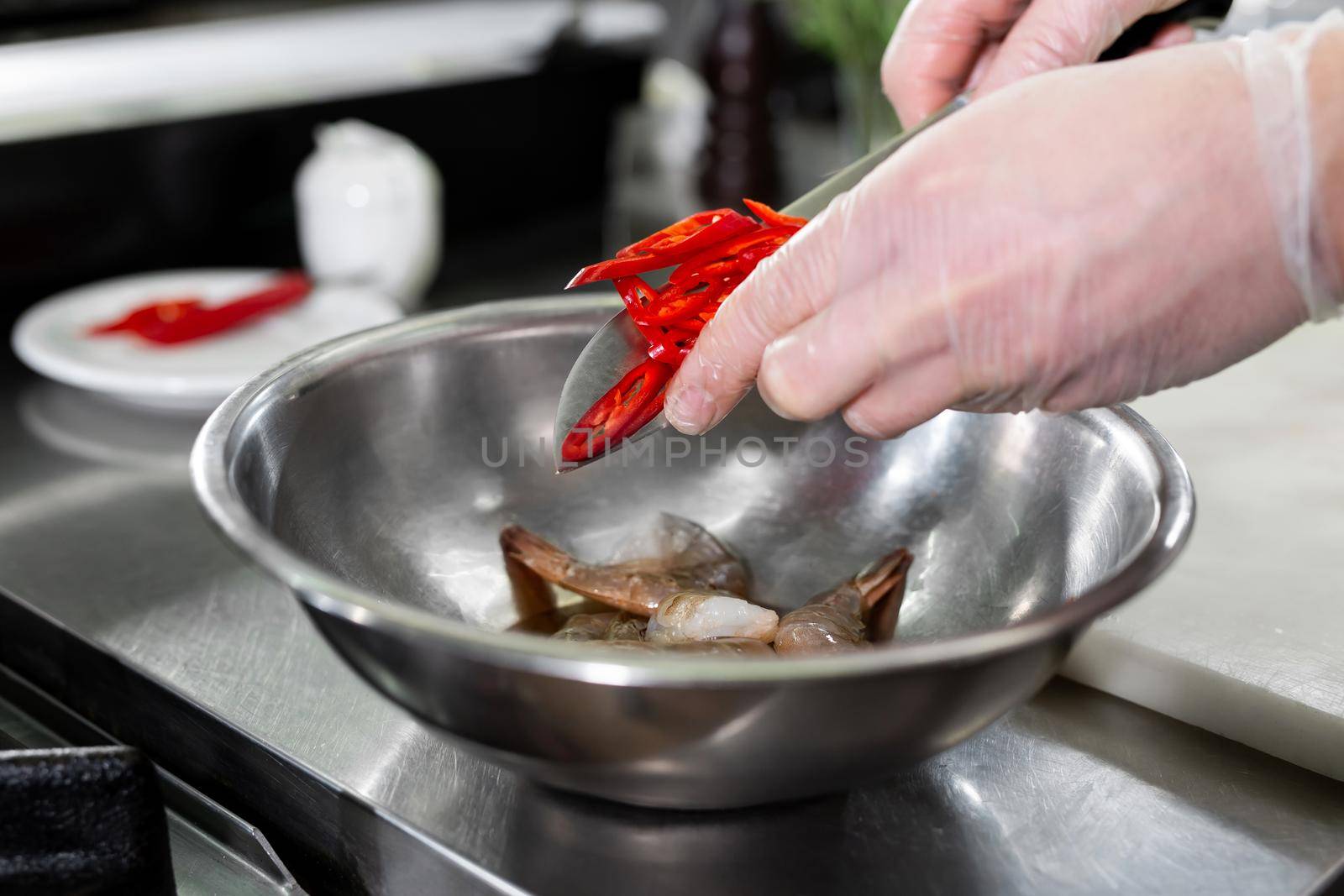 Chef cuts hot chili peppers in the kitchen