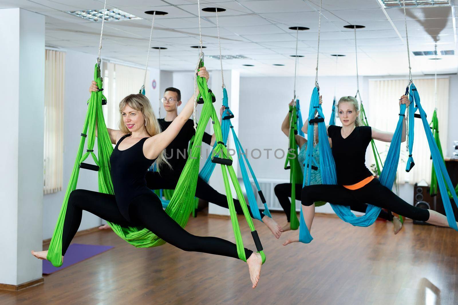 Group of young people practicing yoga on hammock at health club. Fitness, stretch, balance. by StudioPeace