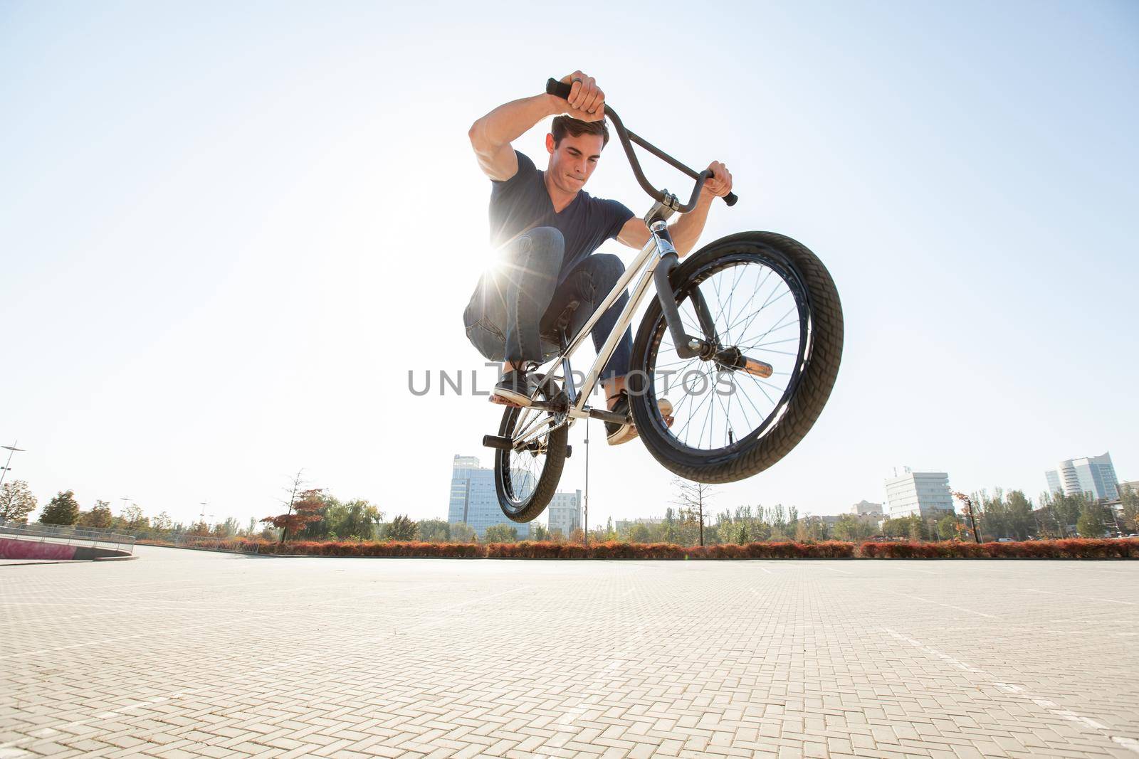 Street portrait of a bmx rider in a jump on the street in the background of the city landscape and the sun. by StudioPeace