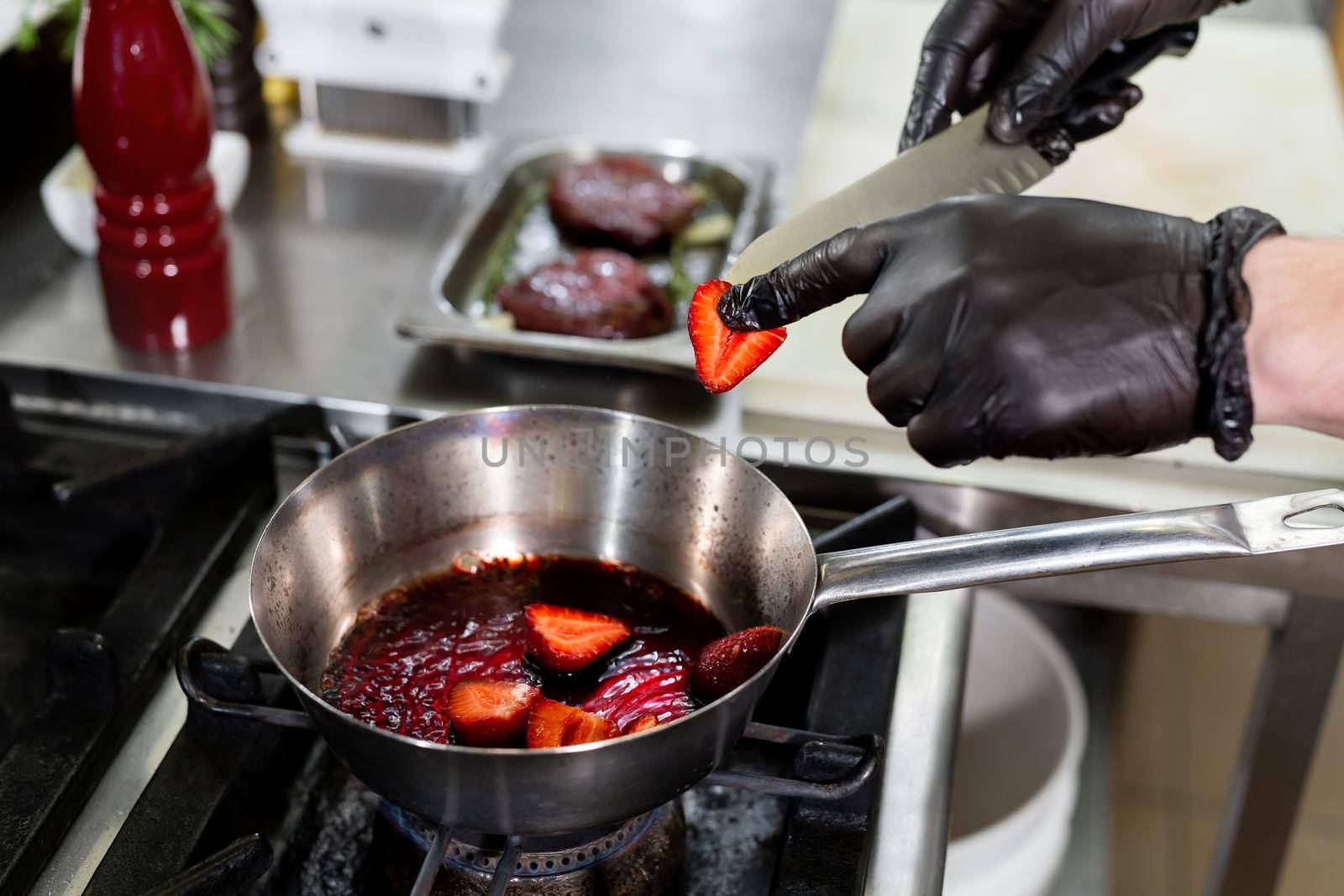 Cook is frying strawberries in a frying pan. by StudioPeace