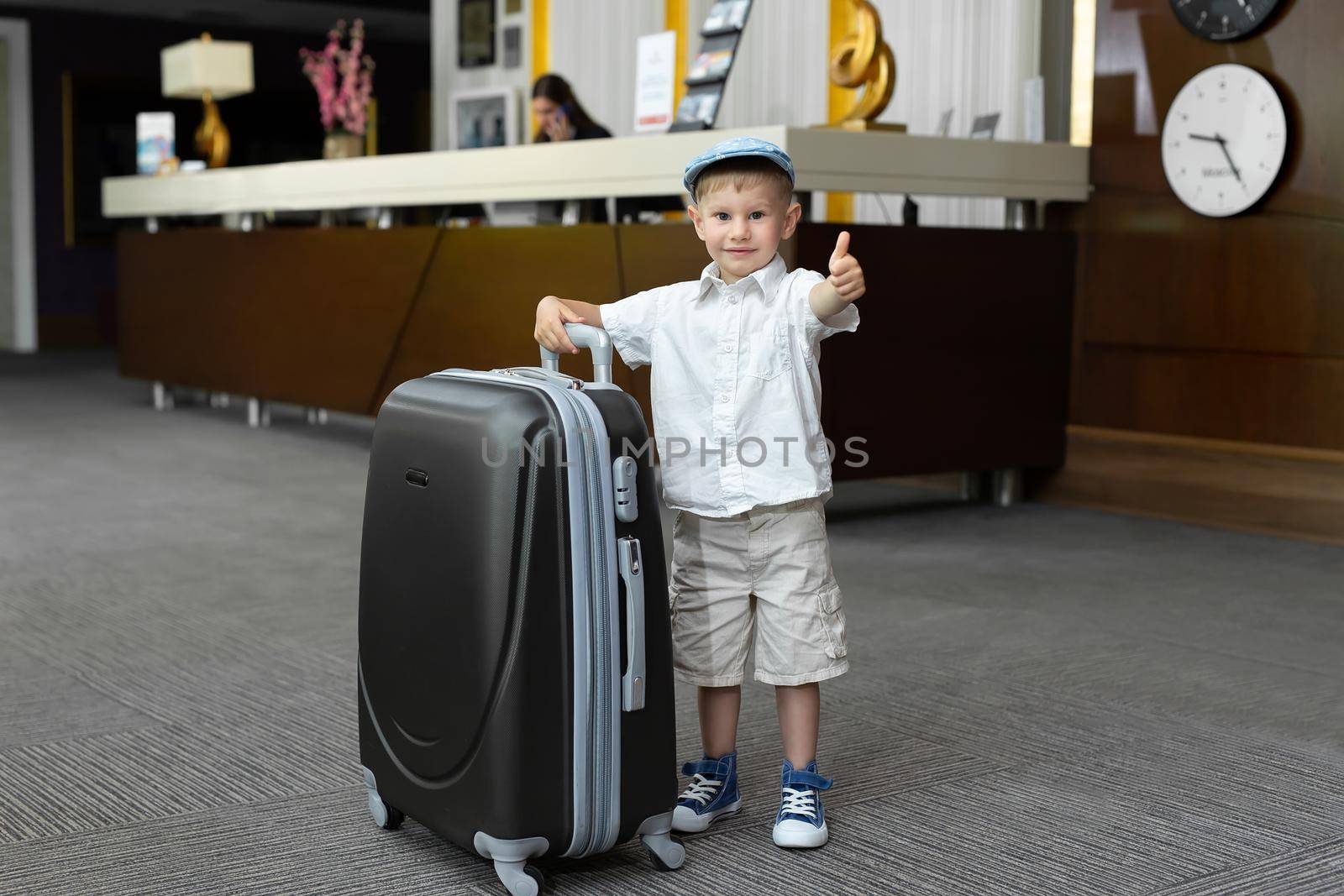 Little boy with a big suitcase in the hotel.