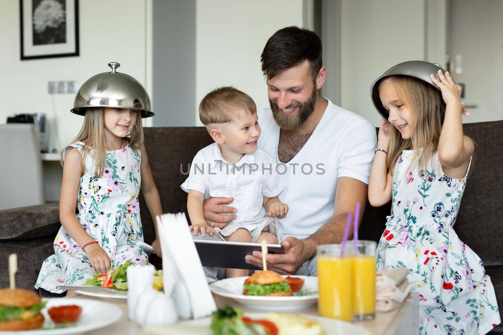 Father of the children has breakfast in the hotel room and play, indulge.