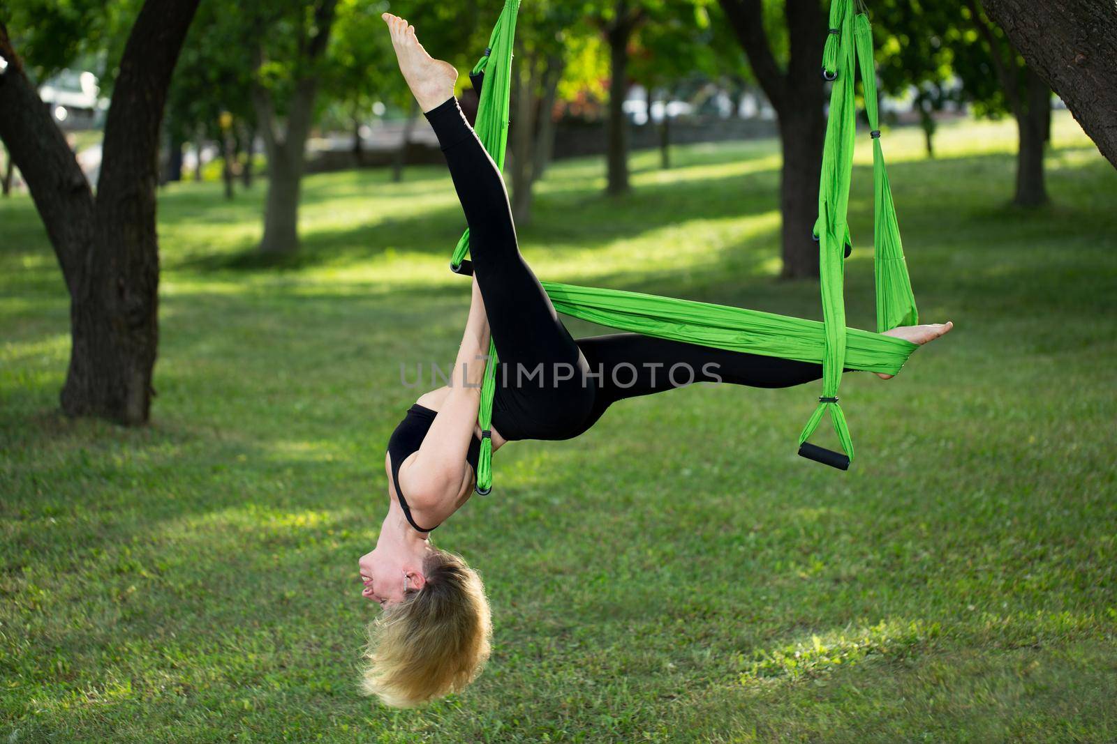 Anti-gravity Yoga, woman doing yoga exercises in the park. by StudioPeace