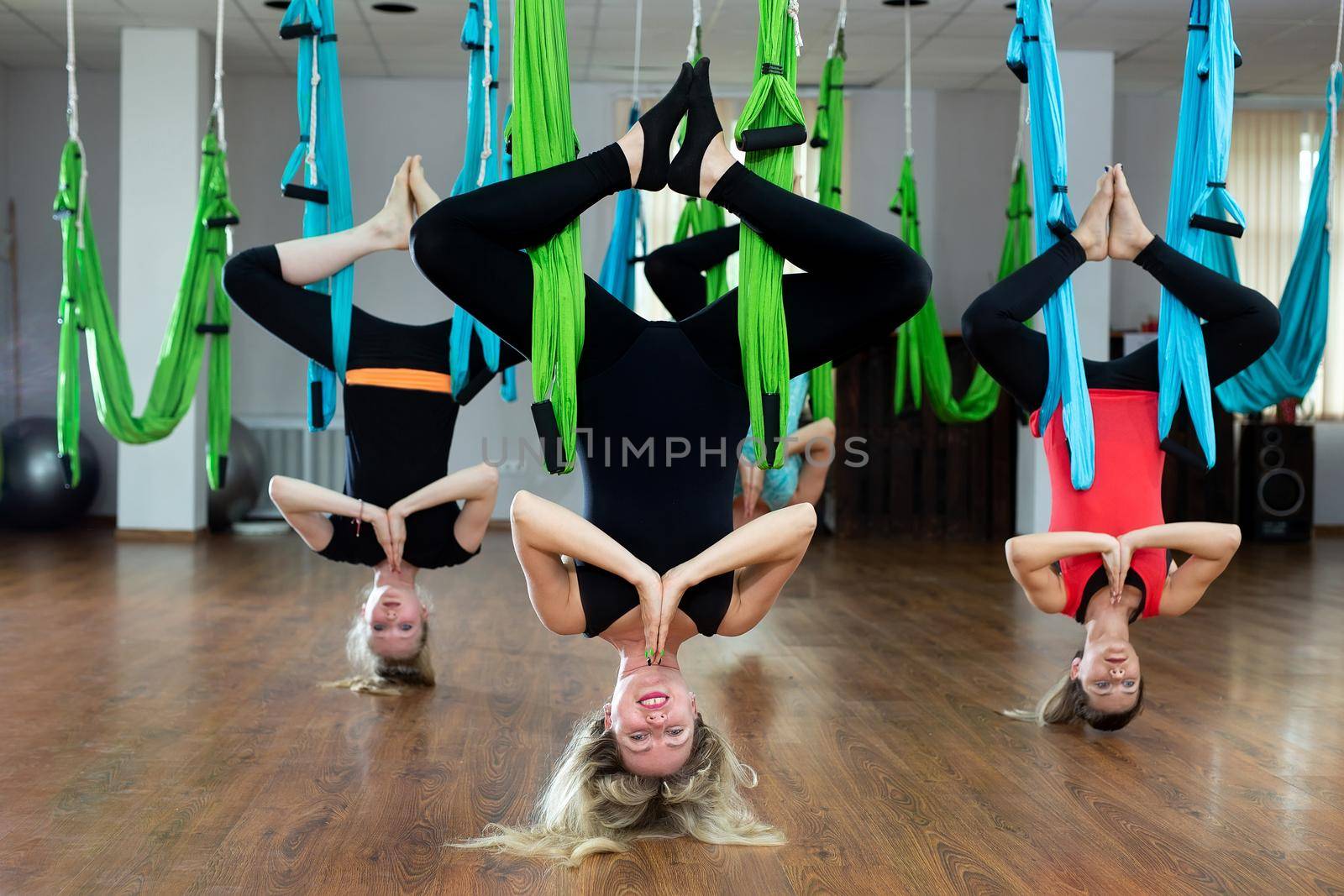 Group of young people practicing yoga on hammock at health club. Fitness, stretch, balance, exercise and healthy lifestyle people. by StudioPeace