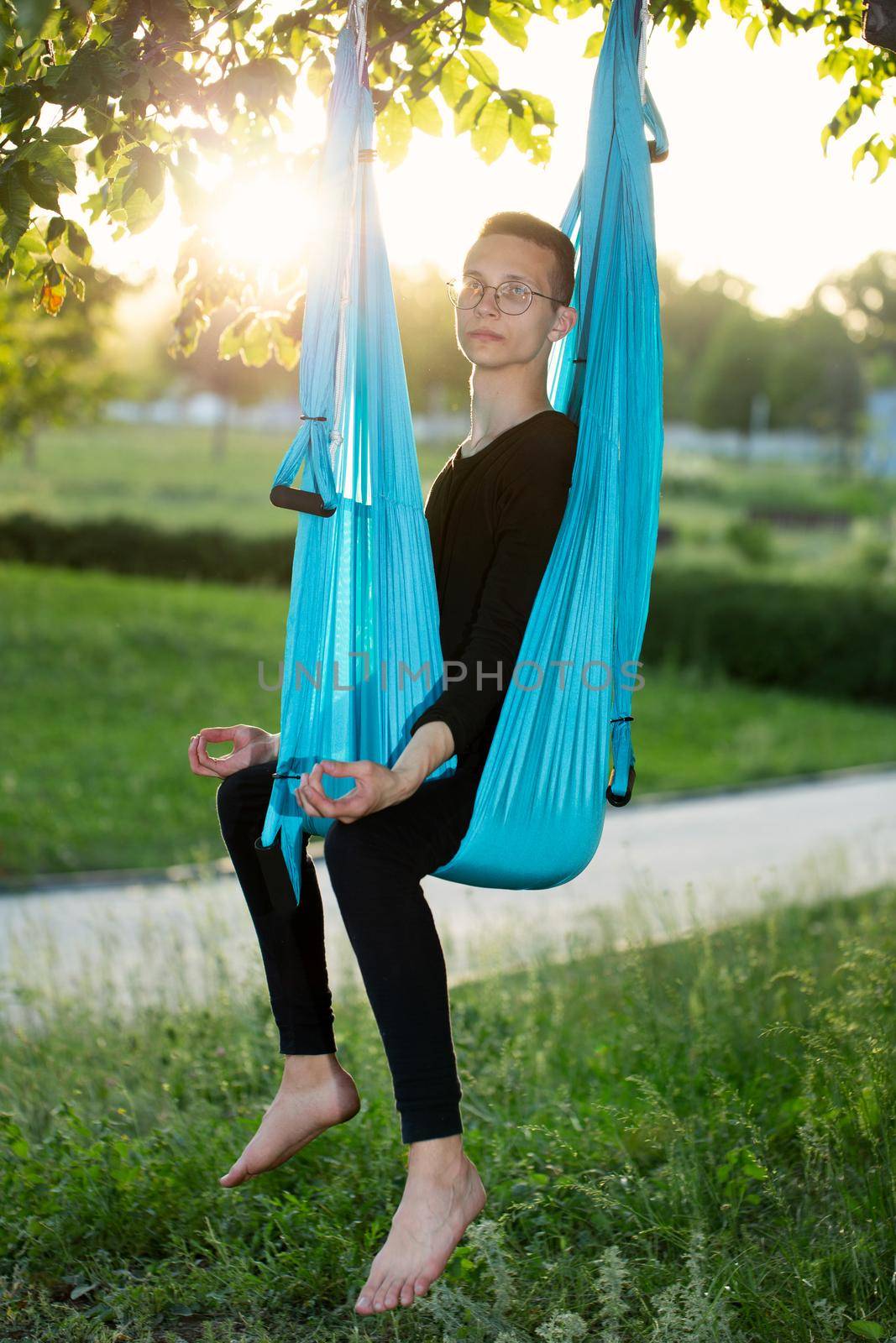 Anti-gravity Yoga, man doing yoga exercises in the park