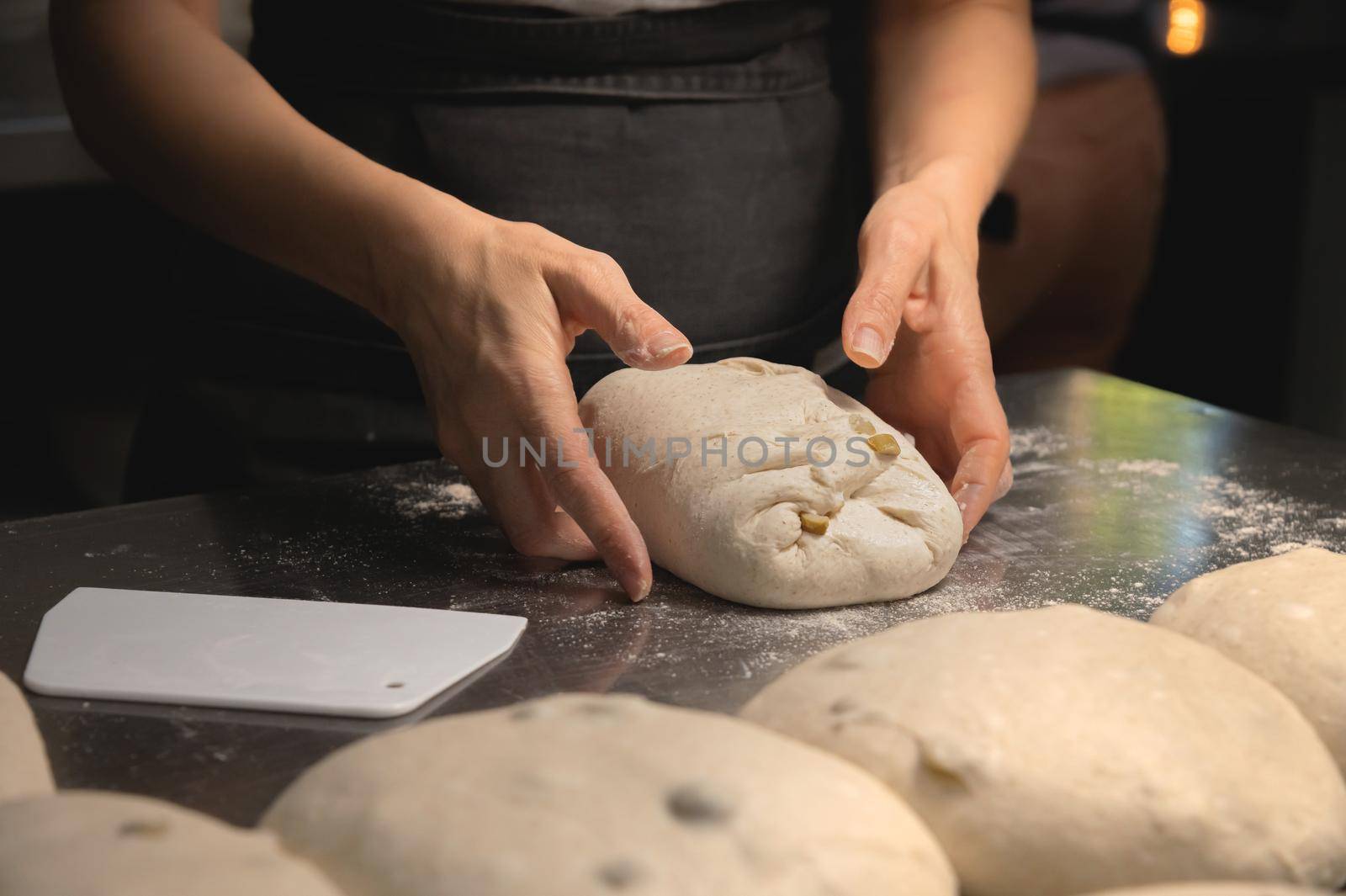 Close-up baker making bread, female hands, kneading dough, cooking