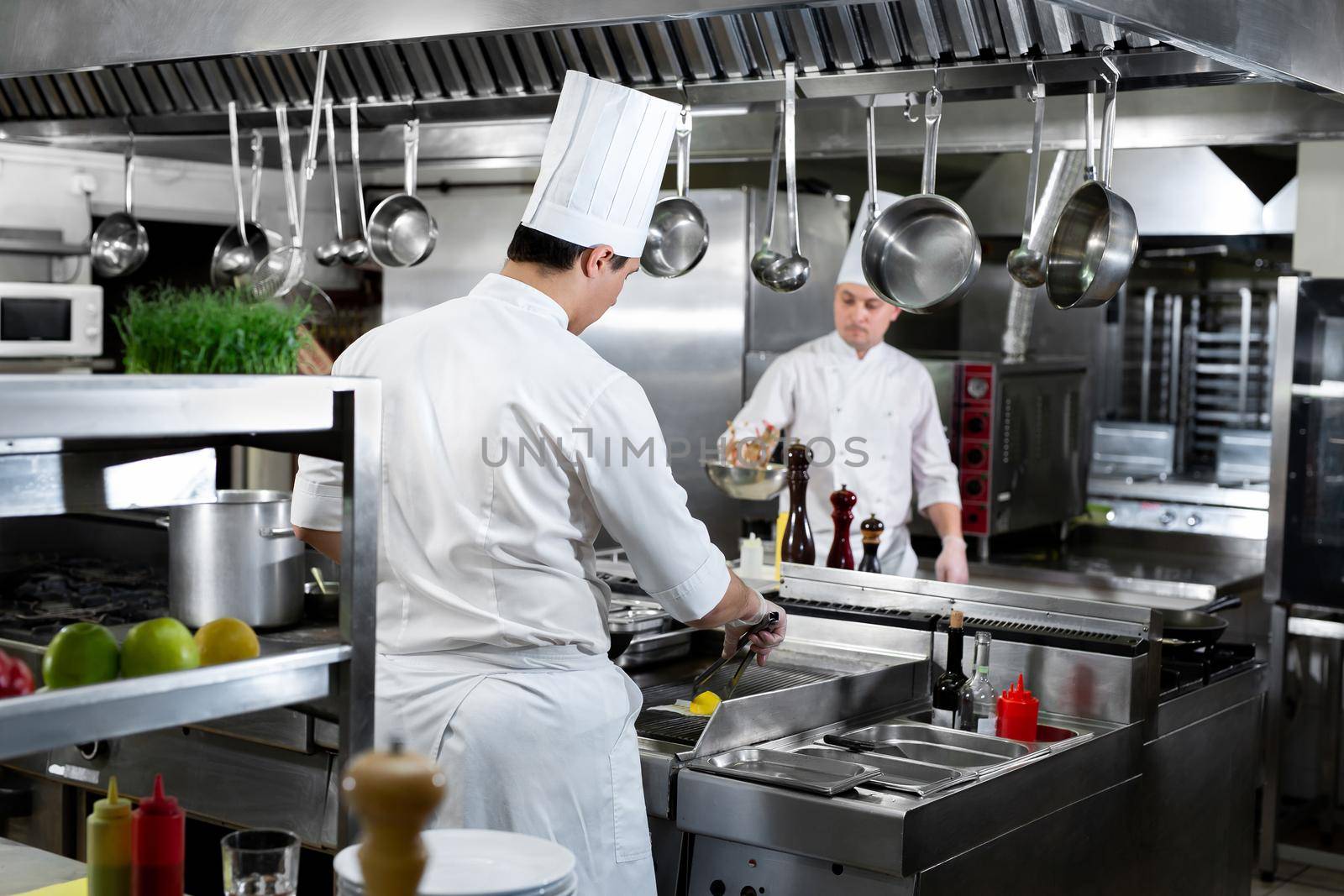 Modern kitchen. Chefs prepare dishes on the stove in the kitchen of a restaurant or hotel by StudioPeace