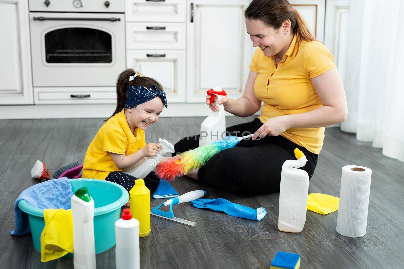 Mom and daughter are ready to clean the apartment, spraying detergent from the spray gun.