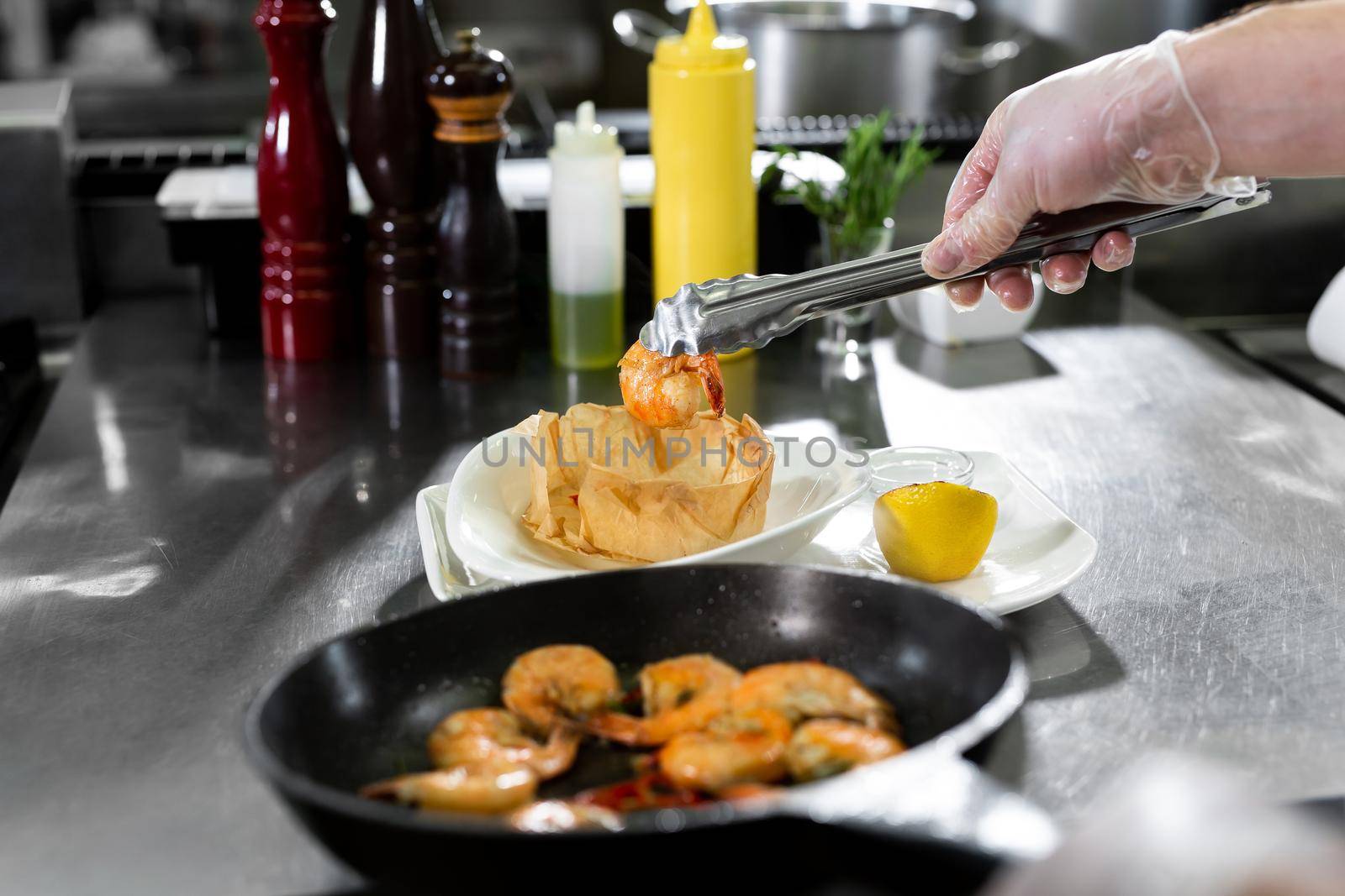 Chef roasts prawns in a frying pan. by StudioPeace