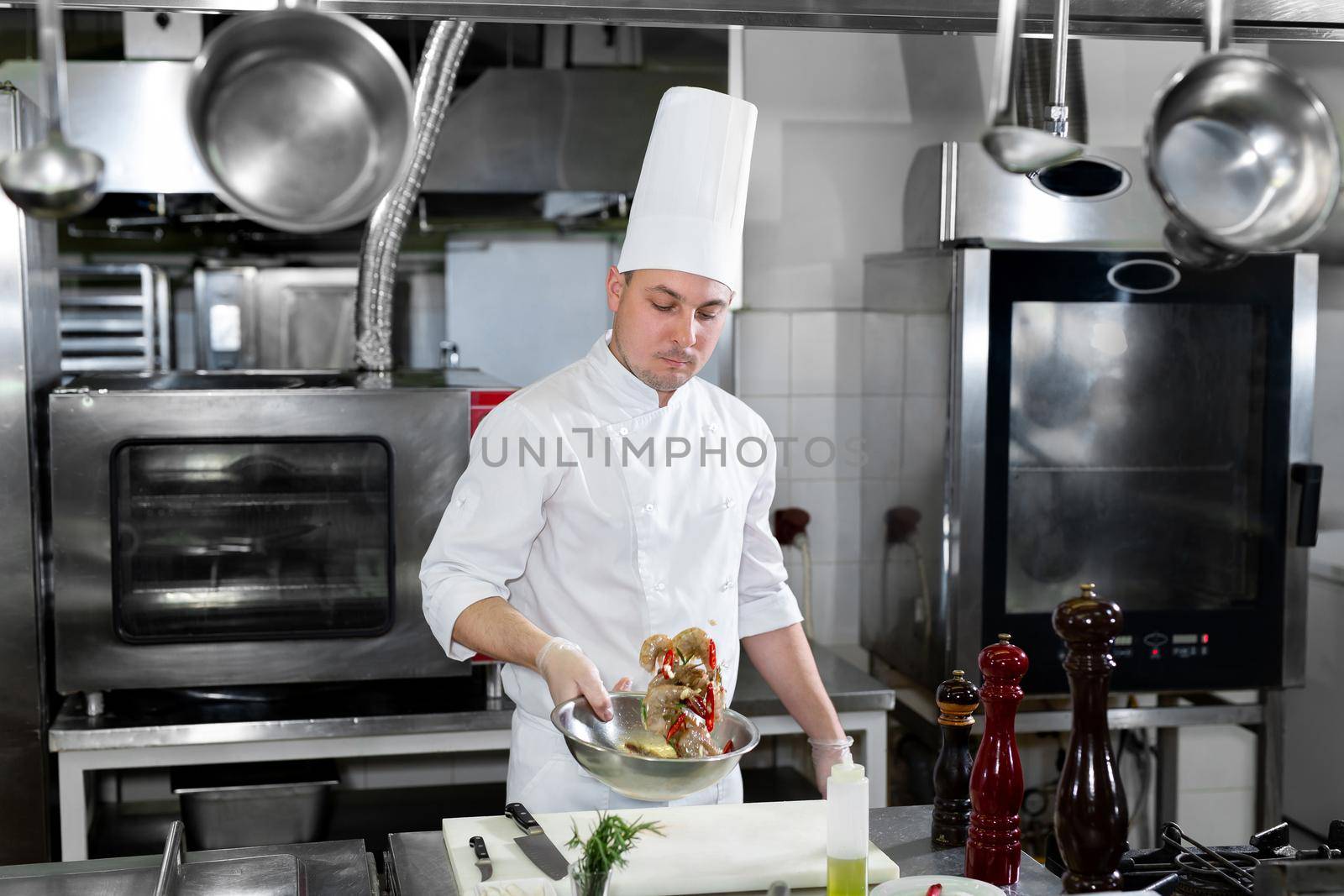 Chef marinates shrimp before frying in the kitchen. by StudioPeace