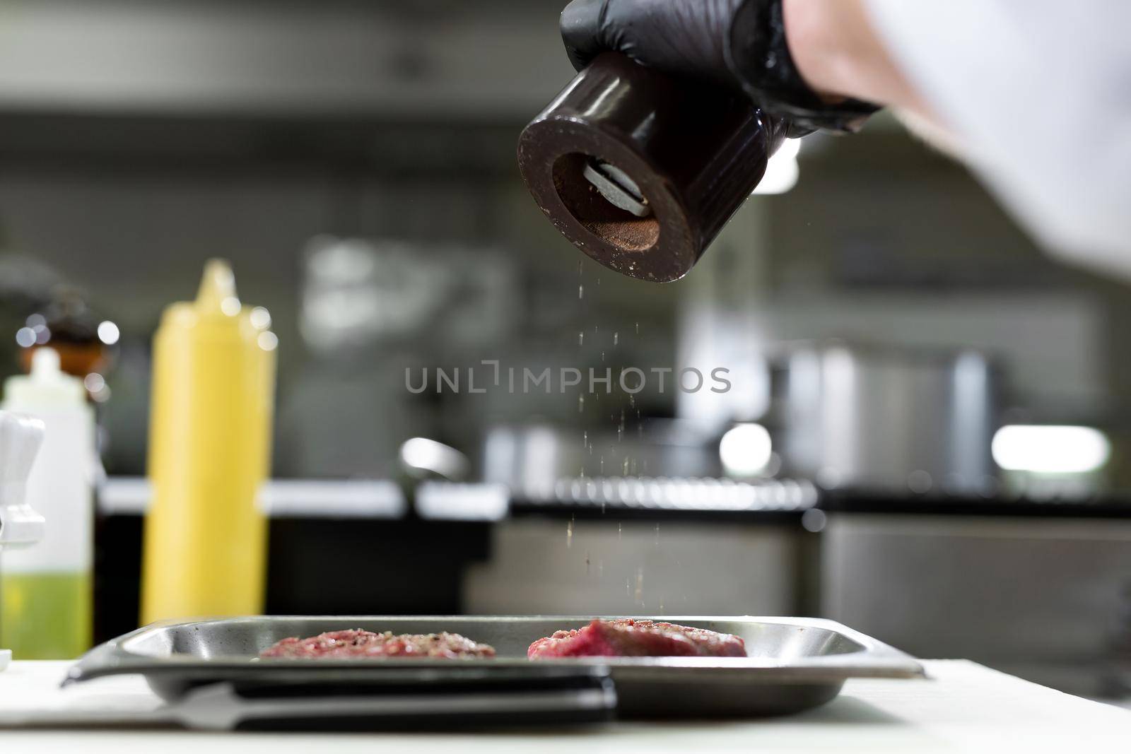 Chef peppering raw beef steak. Professional cook seasoning juicy meat with pepper