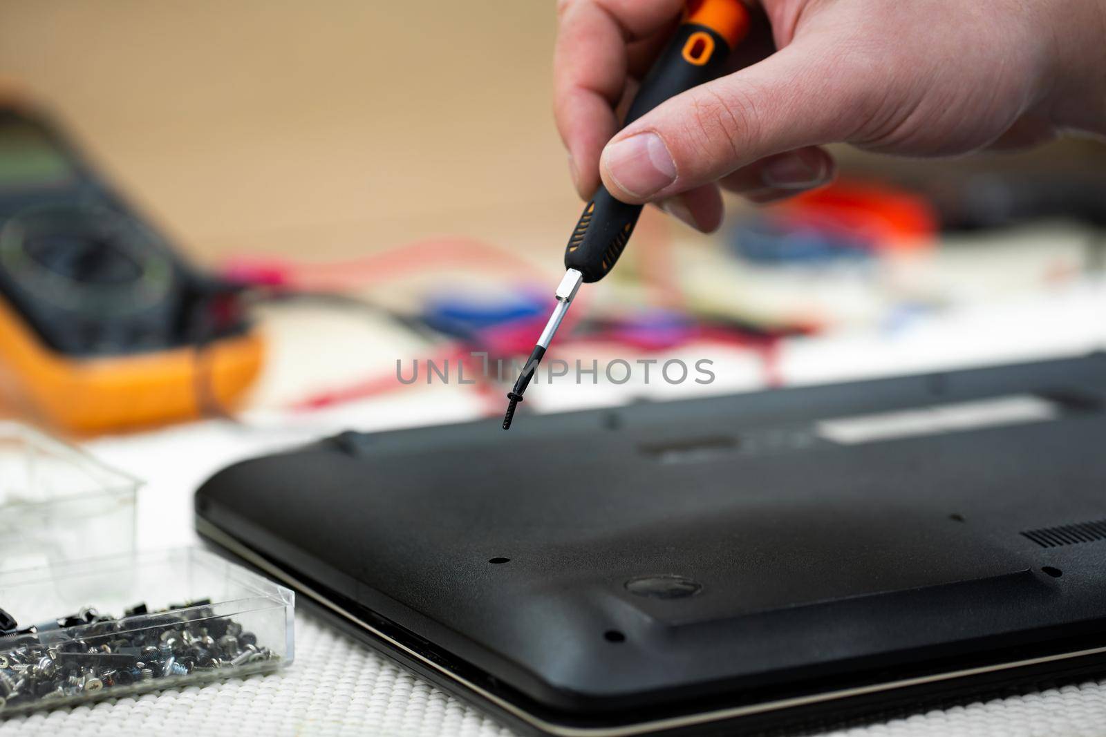 Close-up of a male engineer repairing a laptop in the workshop, disassembling the laptop cover with a screwdriver. by StudioPeace