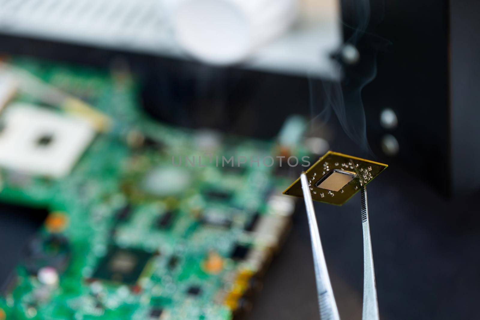 Close-up of a technician repairing a computer chip with a soldering iron, he heats the parts and disconnects them from the Board. by StudioPeace