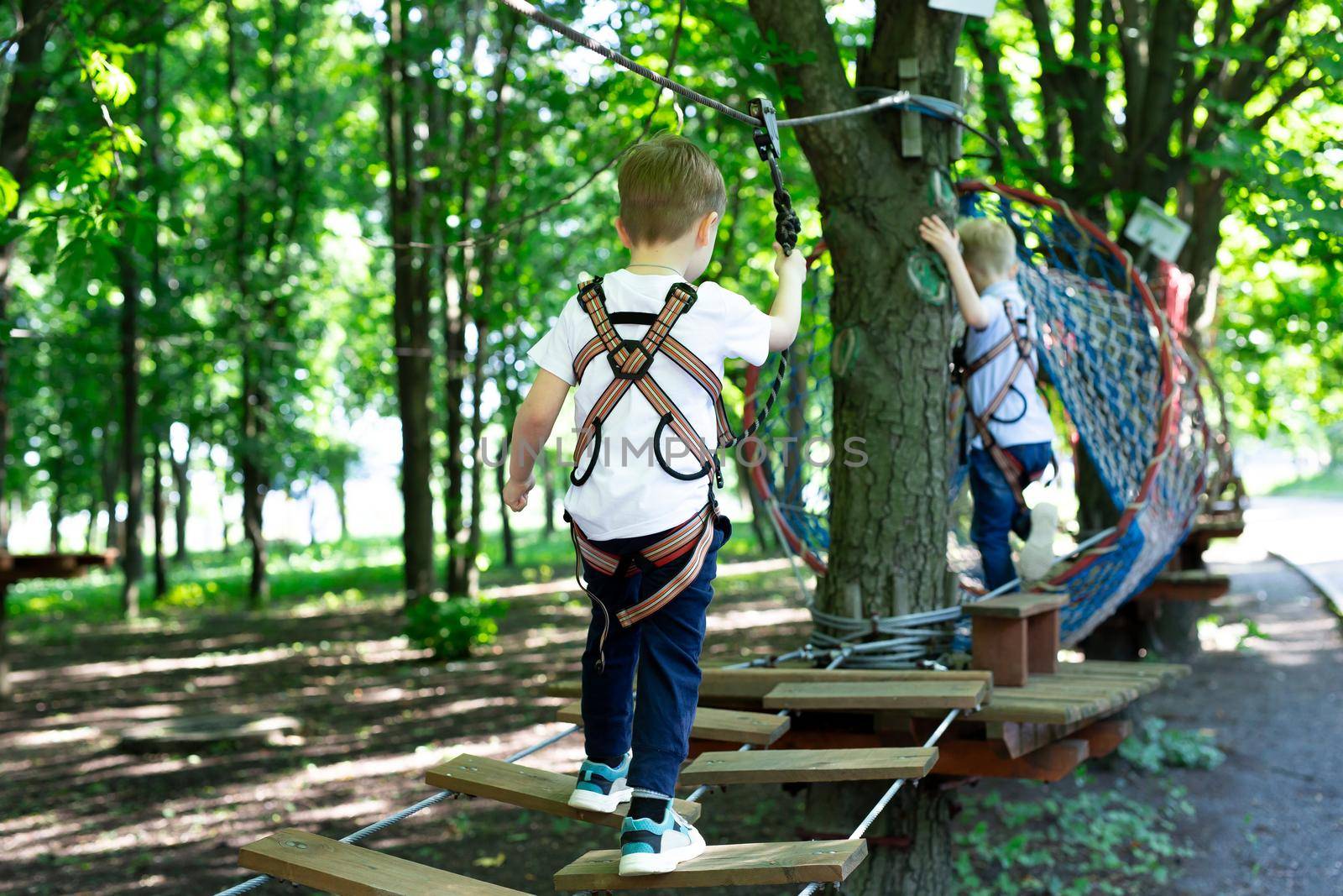Little active boy who climbs on a rope the way to the amusement Park. by StudioPeace