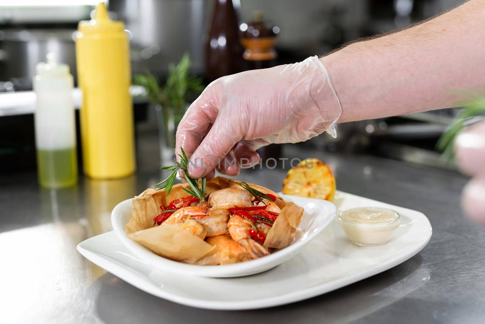 Beautiful man chef preparing dish with shrimps at table in kitchen