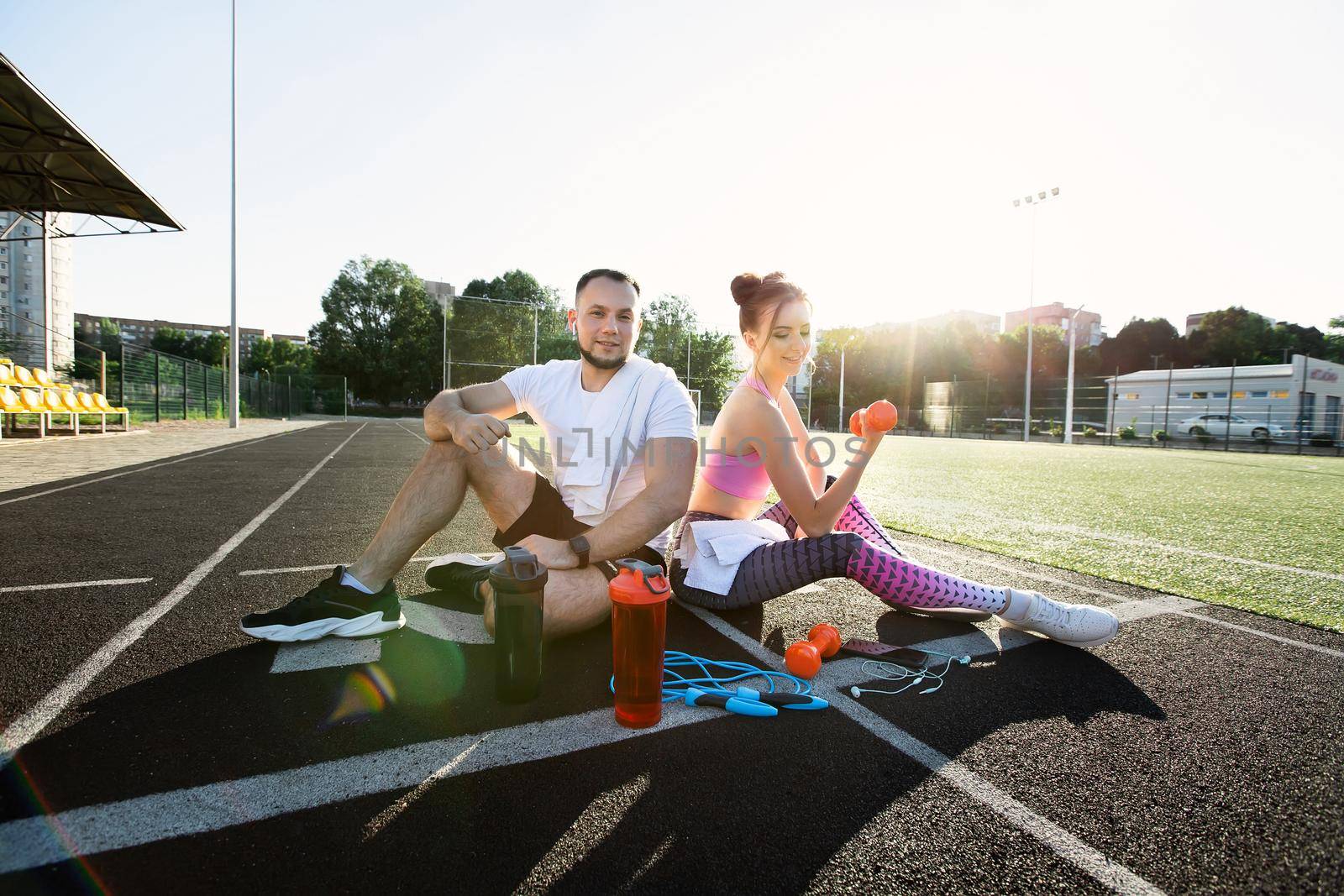 Man and a woman sit in the stadium and laugh. Outdoor sports activities