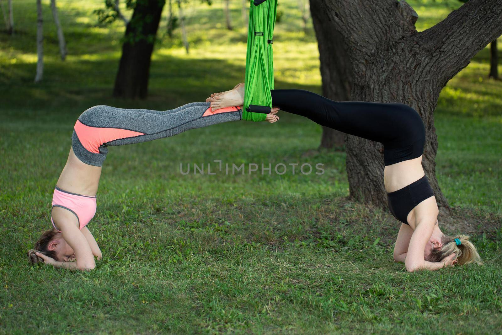 Anti-gravity yoga, women doing yoga exercises in the park. by StudioPeace