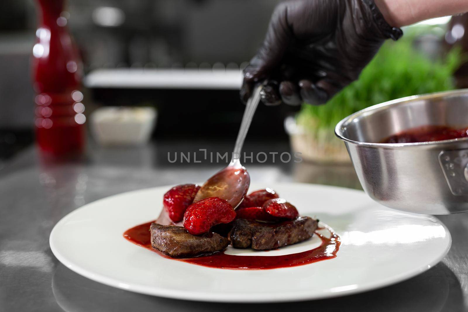 Chef decorates meat with strawberries in a professional kitchen by StudioPeace