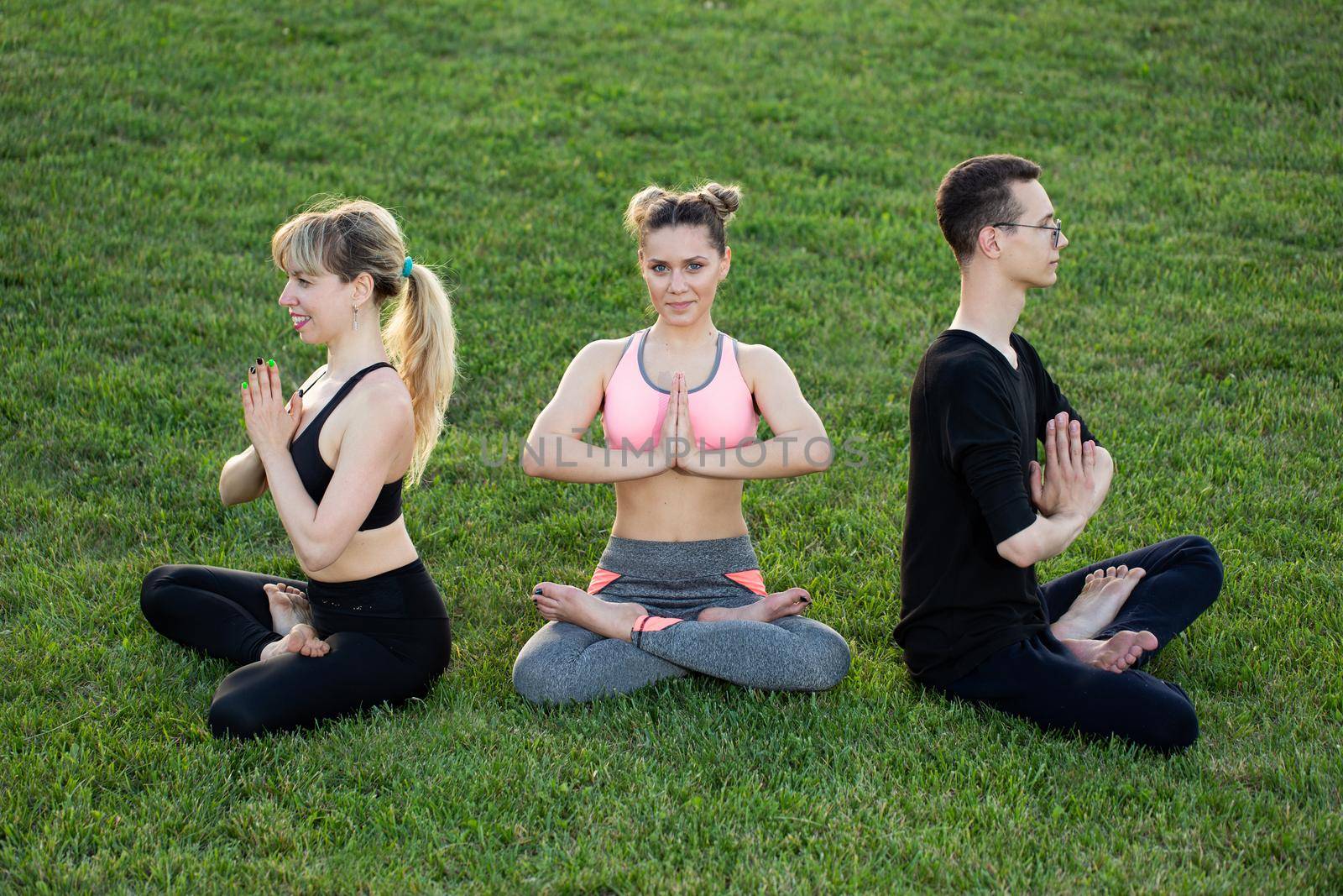 Mature healthy people doing yoga at park. Group people exercising on green grass. by StudioPeace