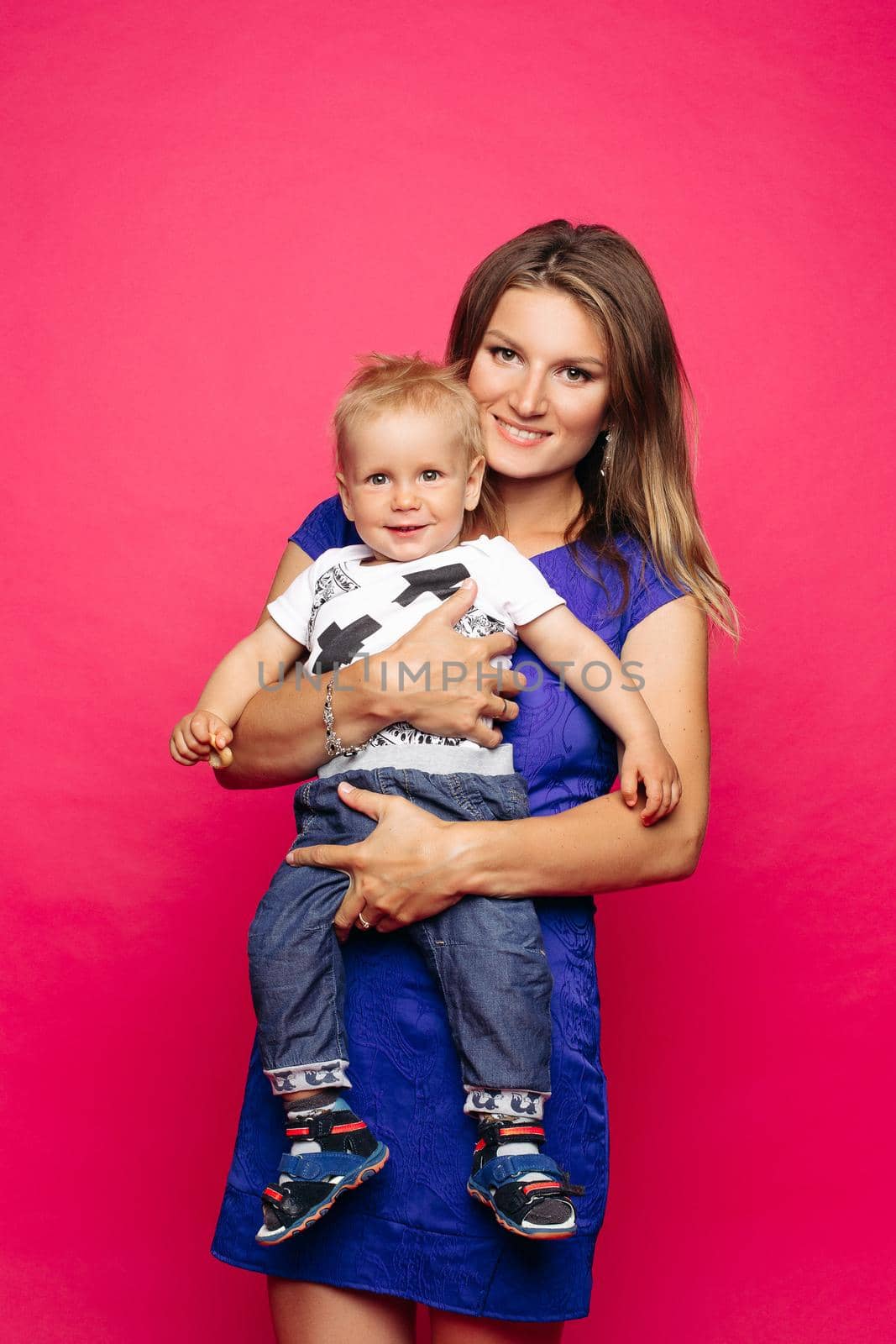 Beautiful young mom with little child, holding anf posing, looking at camera. Pretty and stylish mother loving, embracing her little son. Concept of parent s day, family look and relationship.