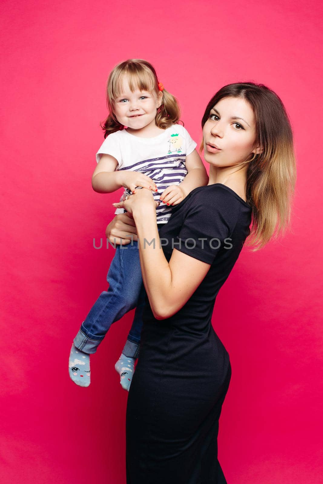 Beautiful young mom with little child, holding anf posing, looking at camera. Pretty and stylish mother loving, embracing her little son. Concept of parent s day, family look and relationship.