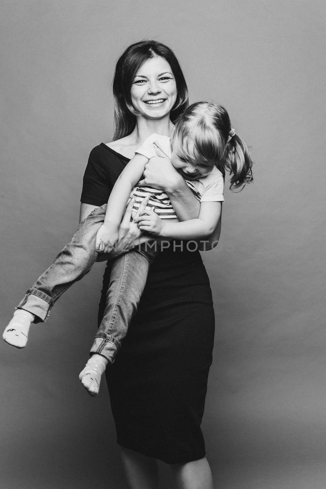 Beautiful young mom with little child, holding anf posing, looking at camera. Pretty and stylish mother loving, embracing her little son. Concept of parent s day, family look and relationship.