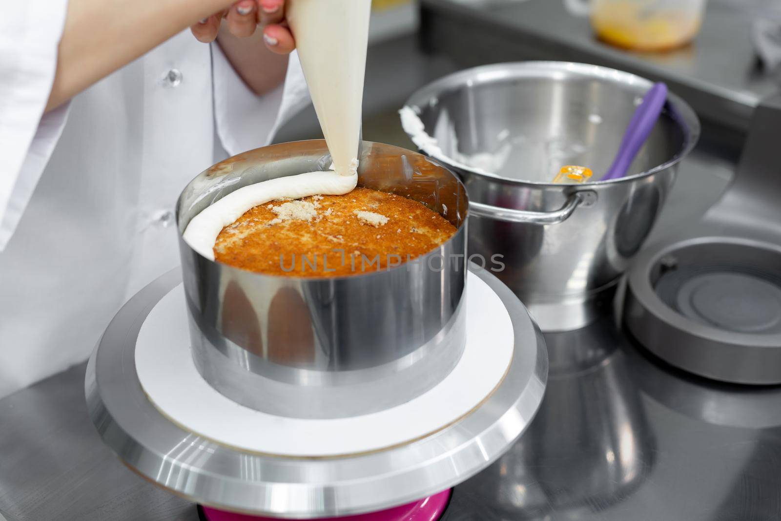 Confectioner apply cream from a pastry bag to the cake.