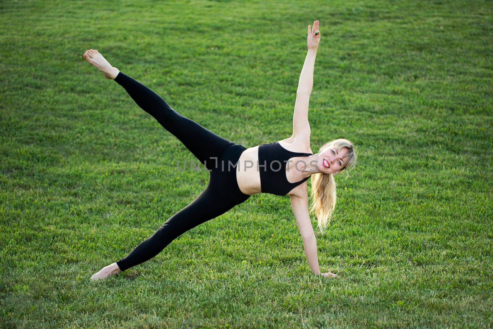 Attractive young caucasian woman standing in yoga pose on the grass