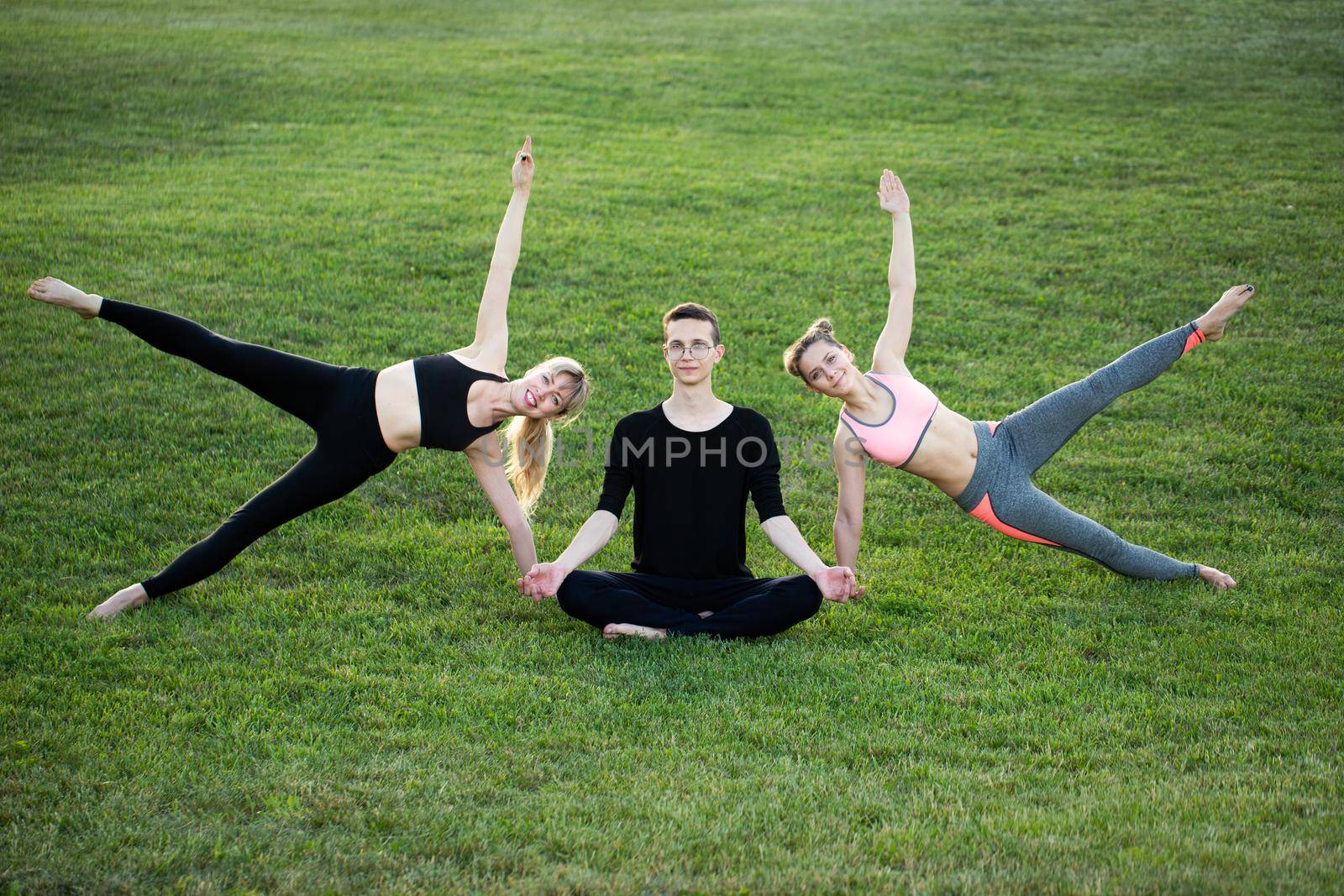 Mature healthy people doing yoga at park. Group people exercising on green grass