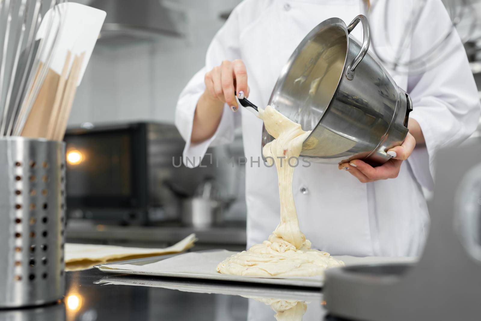 Pastry chef pours the biscuit on the baking parchment.