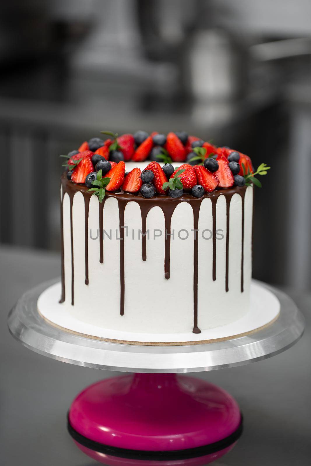 Cake with chocolate streaks and berries in the kitchen. by StudioPeace
