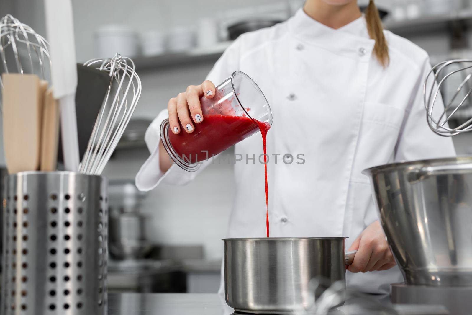 Pastry chef pours strawberry puree into a saucepan.