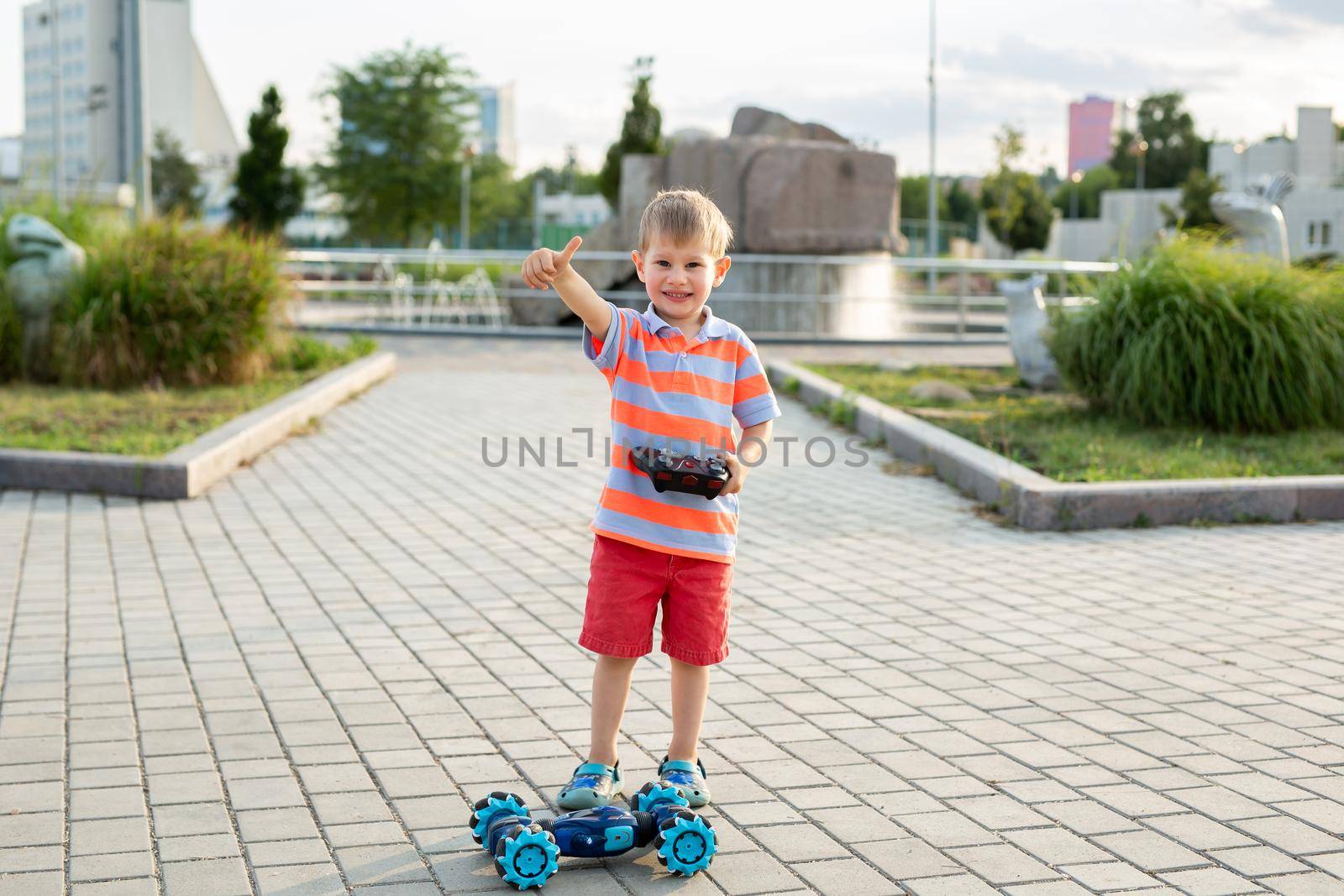 Little boy playing with car on remote control in park. by StudioPeace
