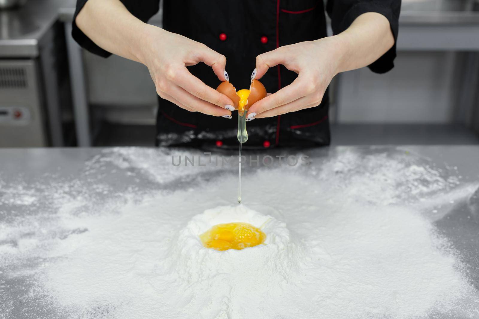 Pastry chef cracking an egg over white flour