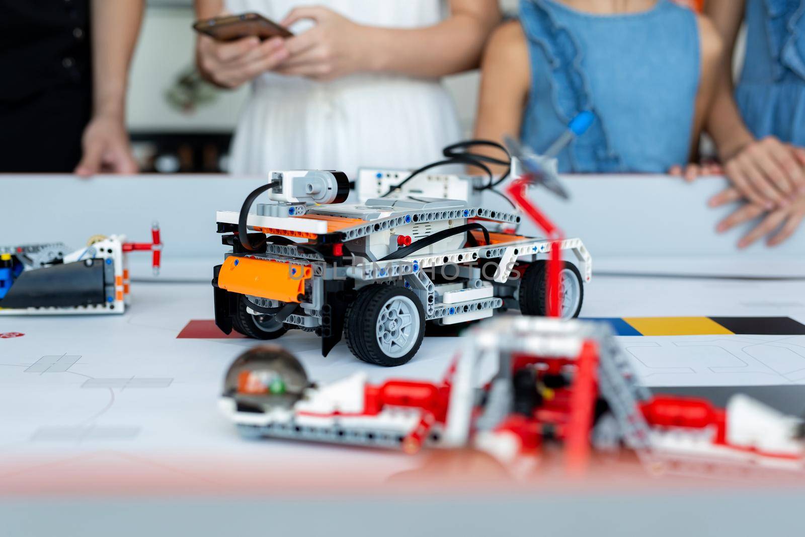 Close-up children control cars robots assembled from a constructor programmed on a computer in a robotics school. by StudioPeace