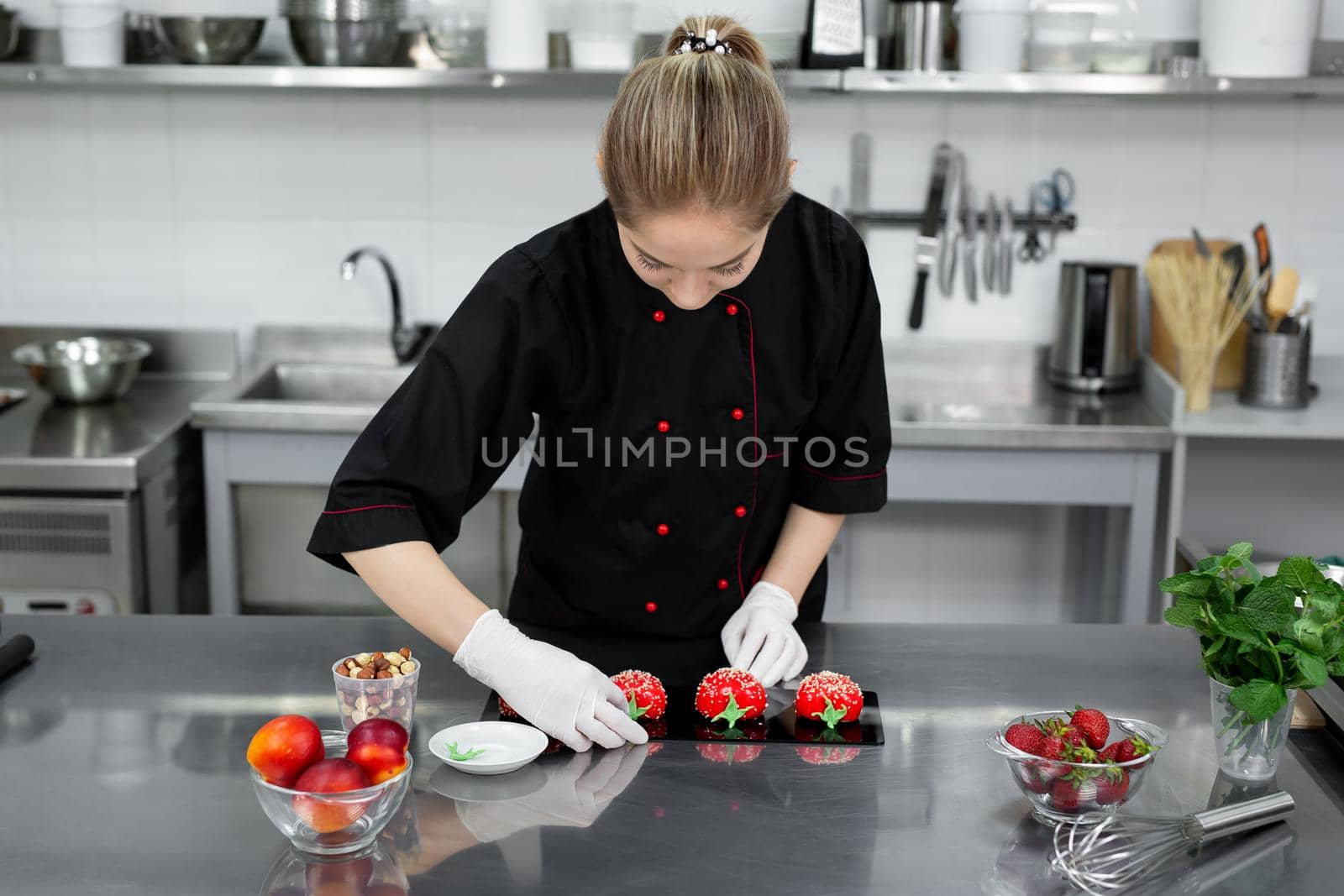 The pastry chef decorates the red mousse cake like a strawberry.