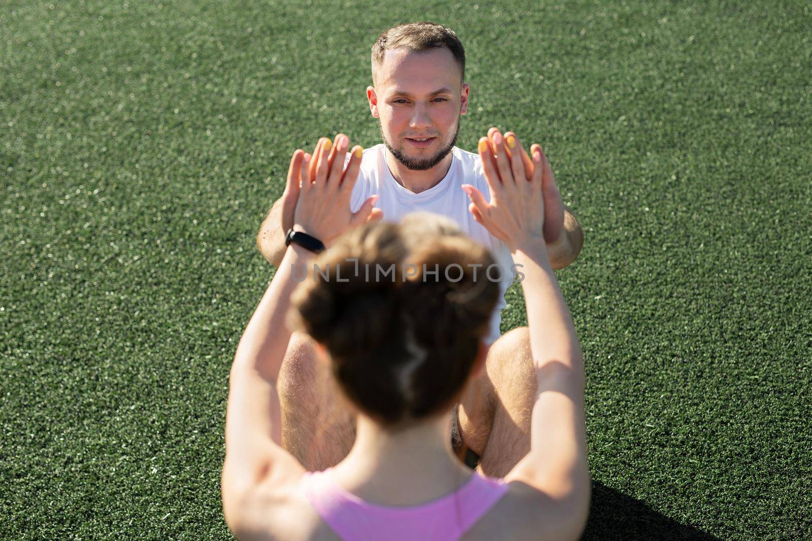 Man and a woman pump their abs in the park on the grass