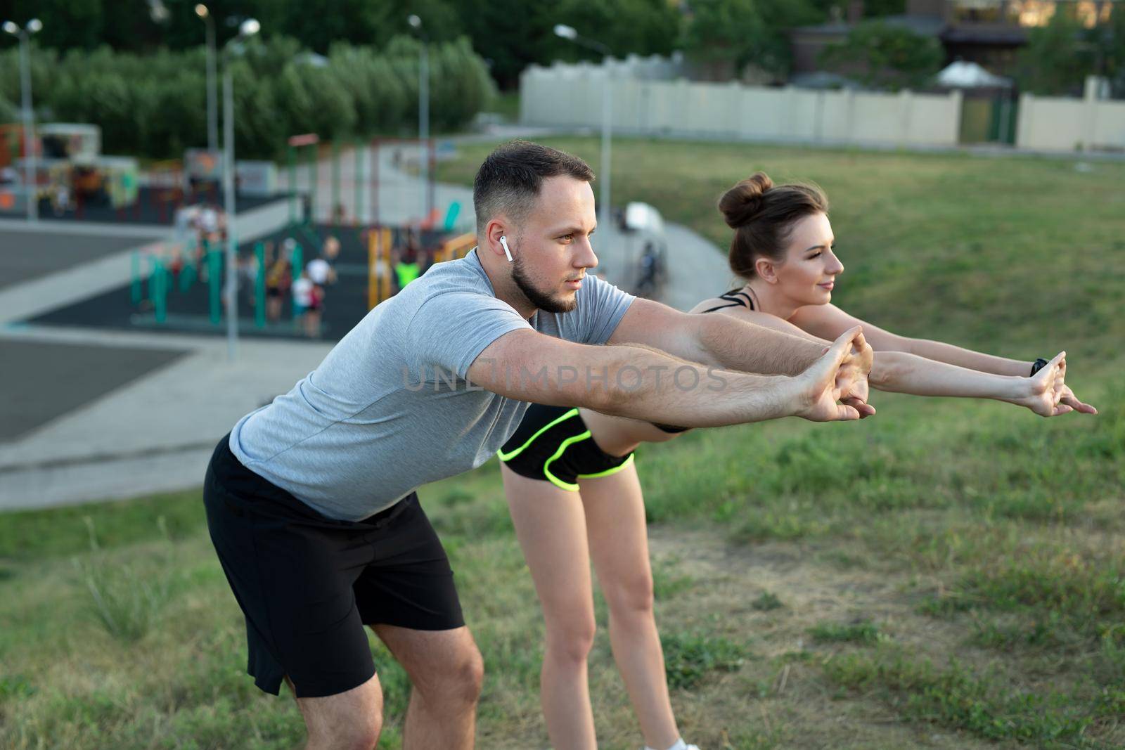 Young couple trains outdoors in a Park in the summer at sunset. by StudioPeace