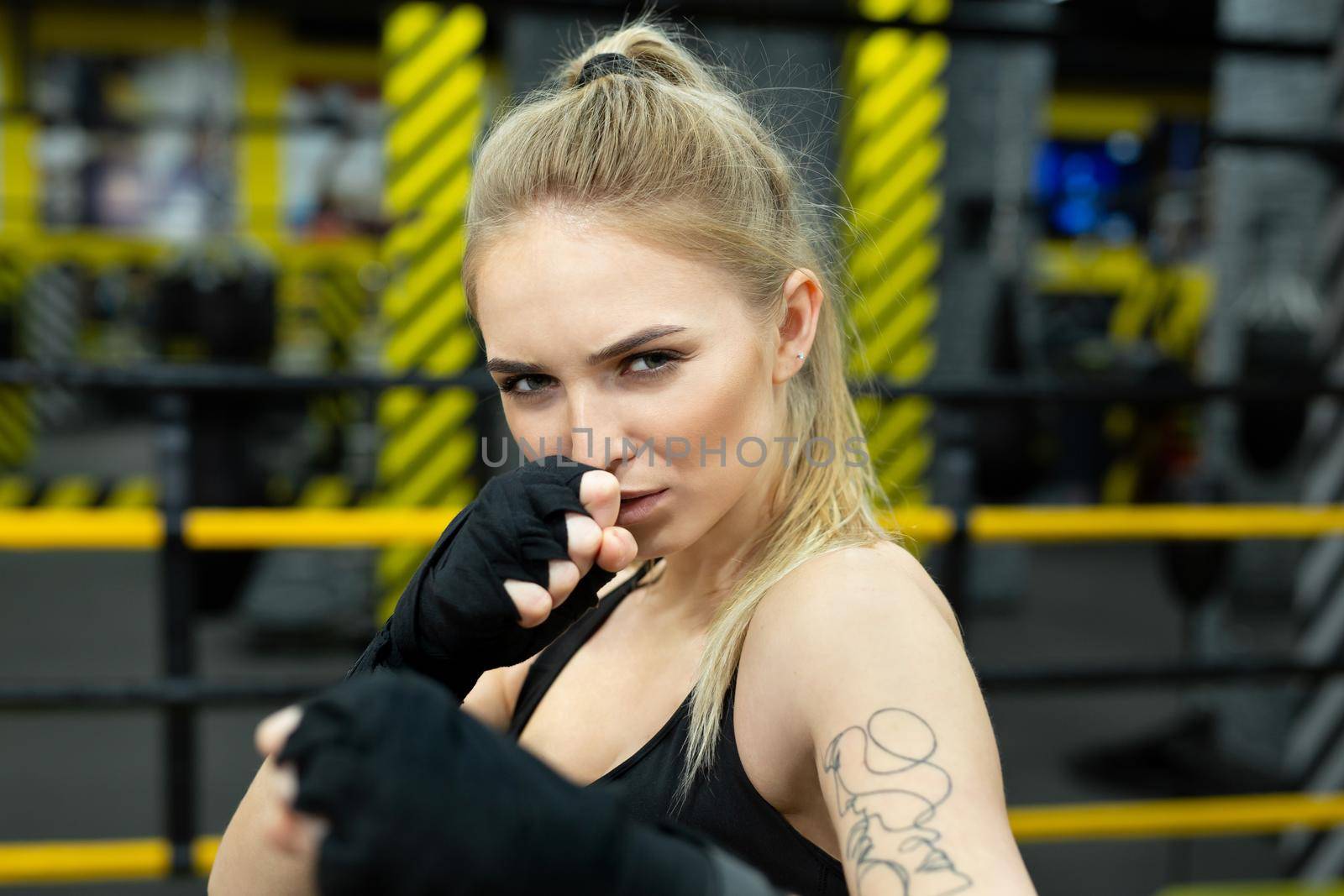 Athletic girl fighter trains in boxing bandages.