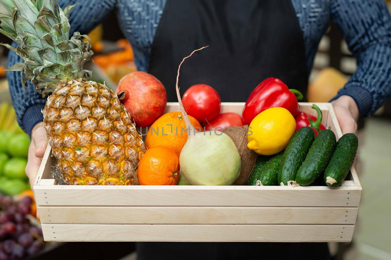 Ecoproduct. A set of fresh vegetables and fruits in a box, which the man holds in his hands. The man in the apron. Vegetable Set
