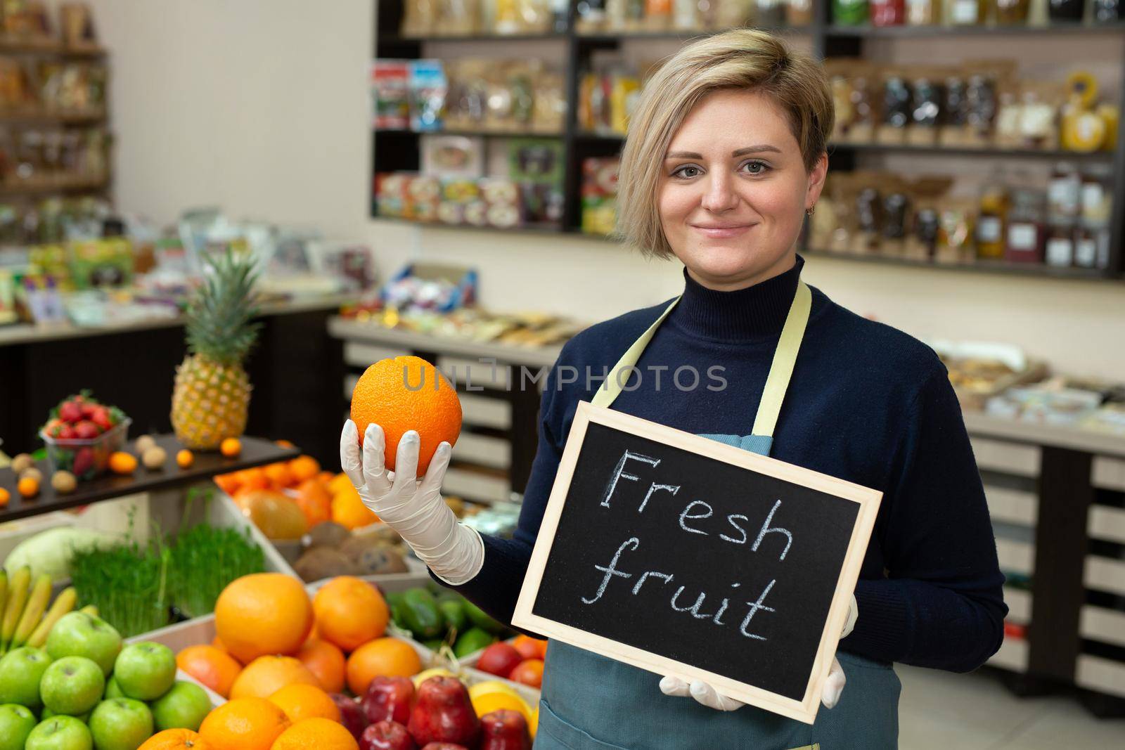 Portrait of a young saleswoman with a sign in her hands fresh fruit.