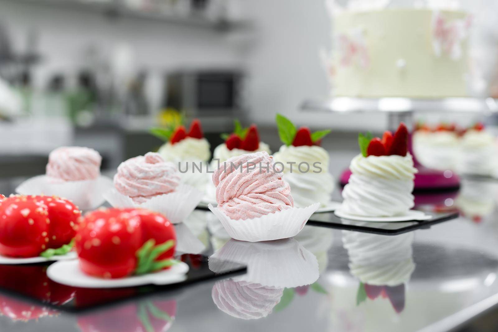 Pavlova meringue, marshmallows and mousse cake on the table in the pastry shop by StudioPeace