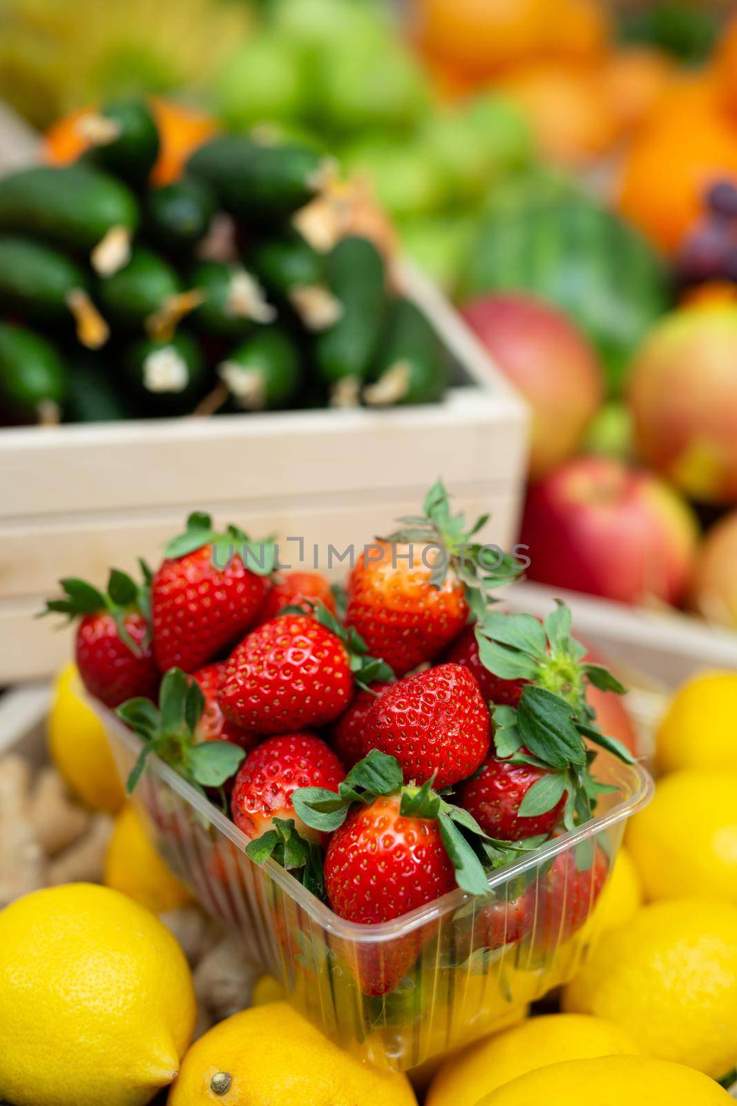 Tray of strawberries on the counter of a vegetable store among vegetables and fruits.