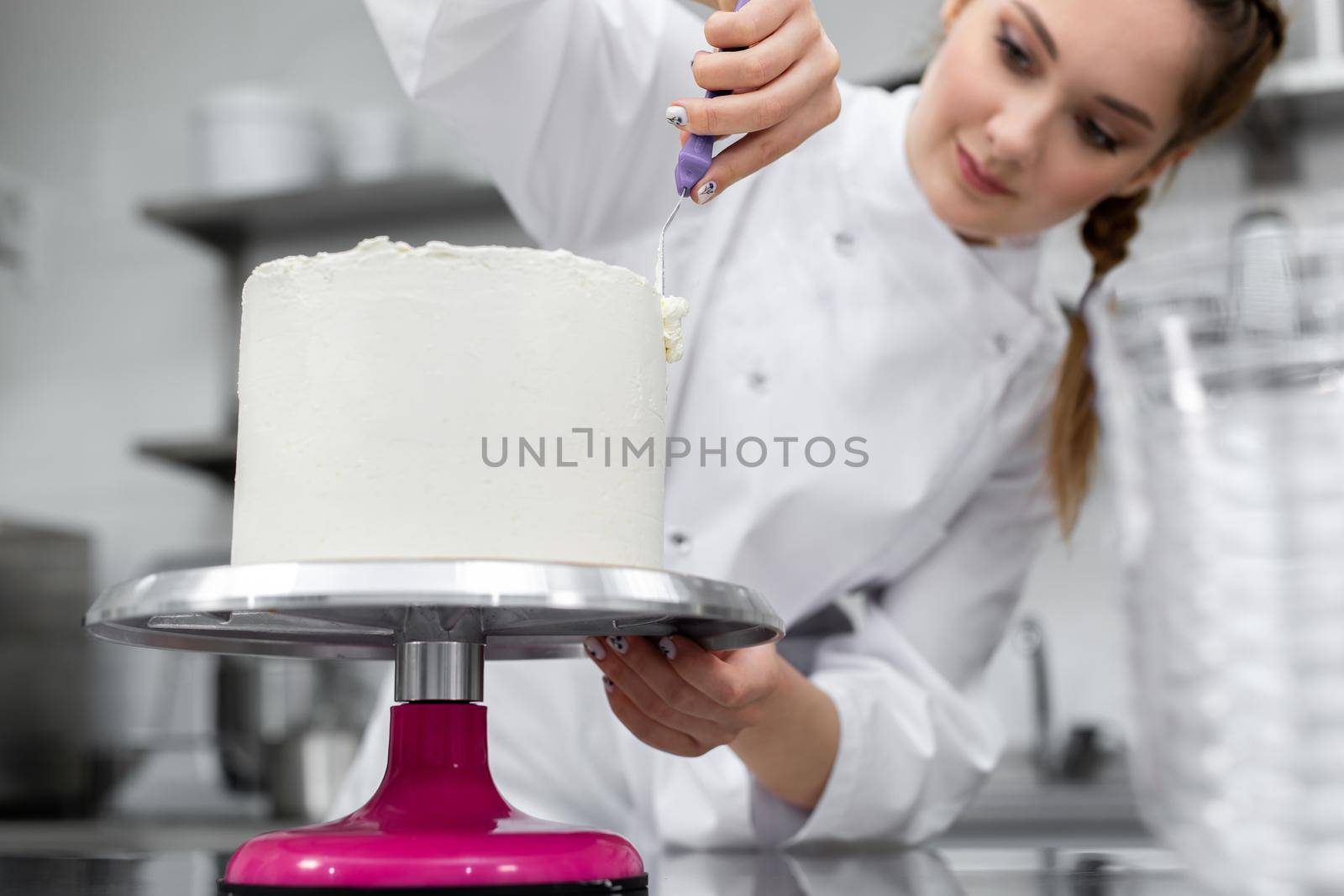The pastry chef levels the cake with cream