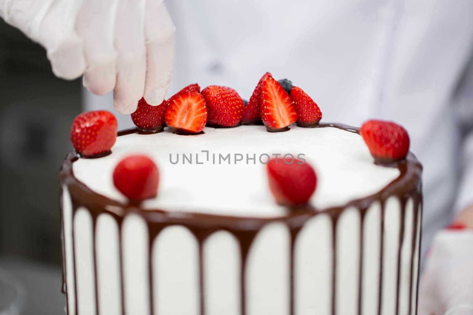 Pastry chef decorates the cake with chocolate streaks of strawberries by StudioPeace