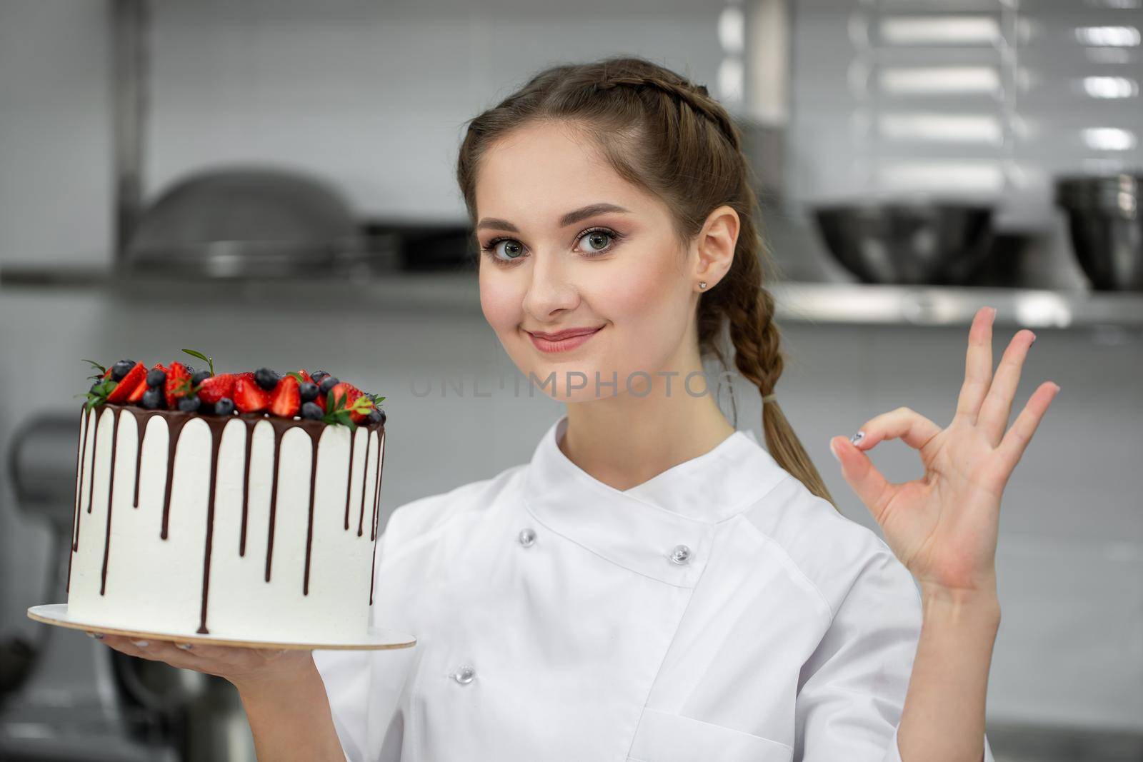 Close-up of a cake in the hands of a pastry chef by StudioPeace
