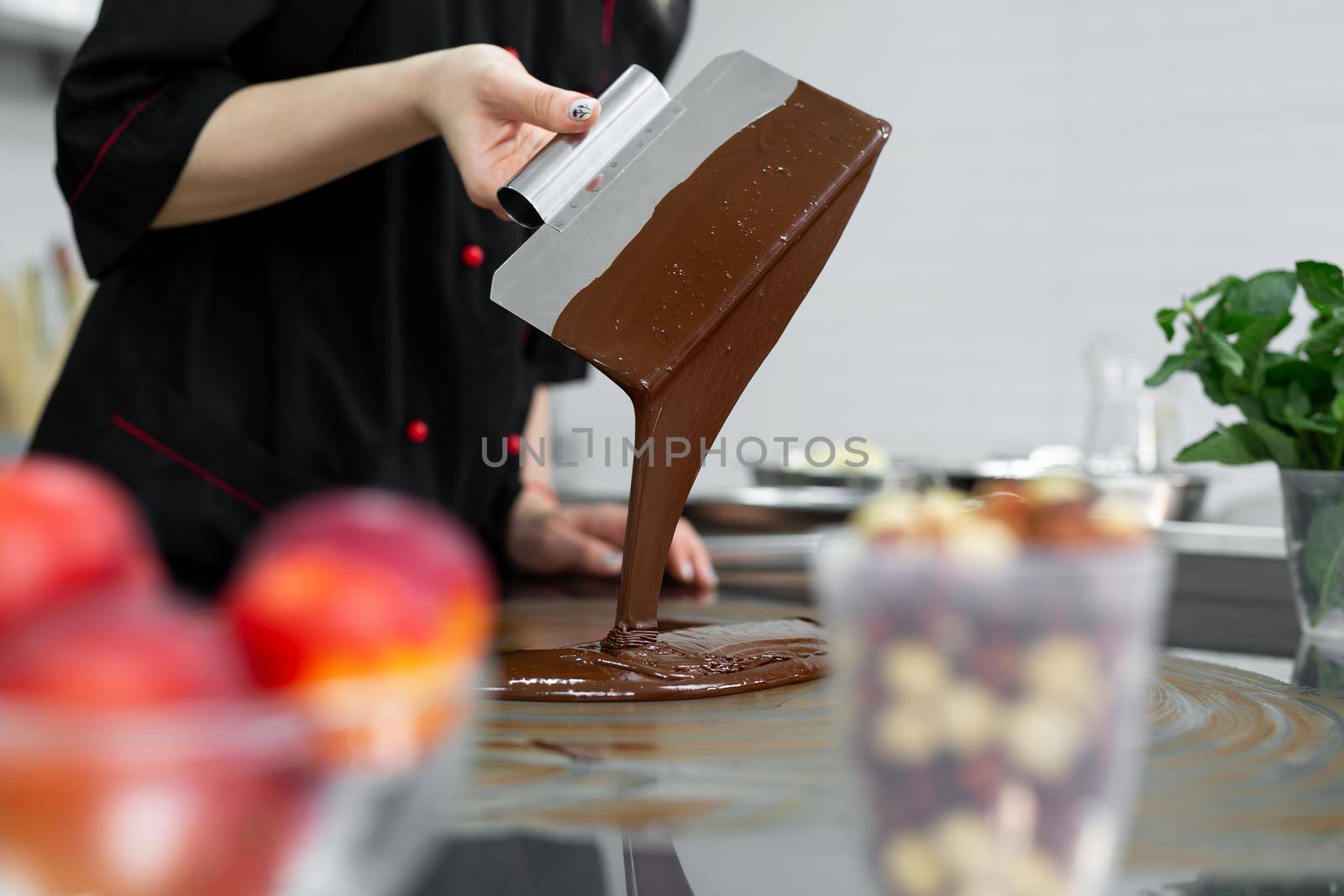 Close-up of a pastry chef using spatulas tempering molten chocolate