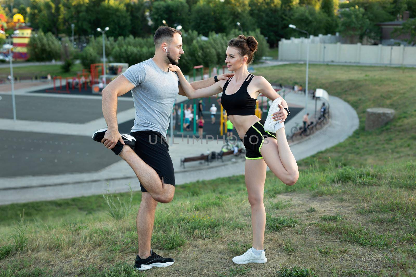 Young couple trains outdoors in a Park in the summer at sunset. by StudioPeace