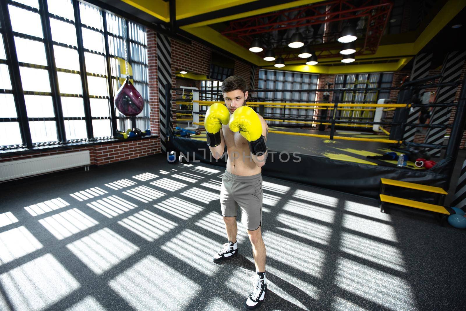 Collected sportsman in the boxing hall practicing boxing punches during training